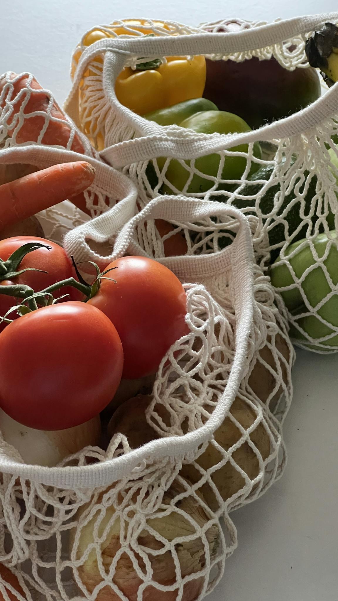 Close-up of vibrant vegetables in reusable mesh bags, highlighting sustainable food storage.