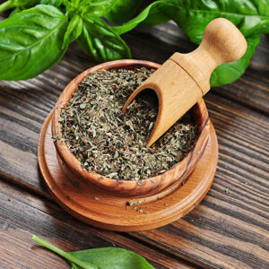 Dry basil in wooden bowl and fresh basil on wooden background