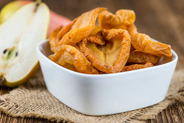 Wooden table with dried pears (selective focus; close up shot)