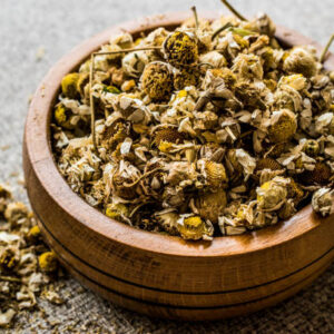 Dried camomile flower tea in wooden bowl (papatya bobune). organic concept.