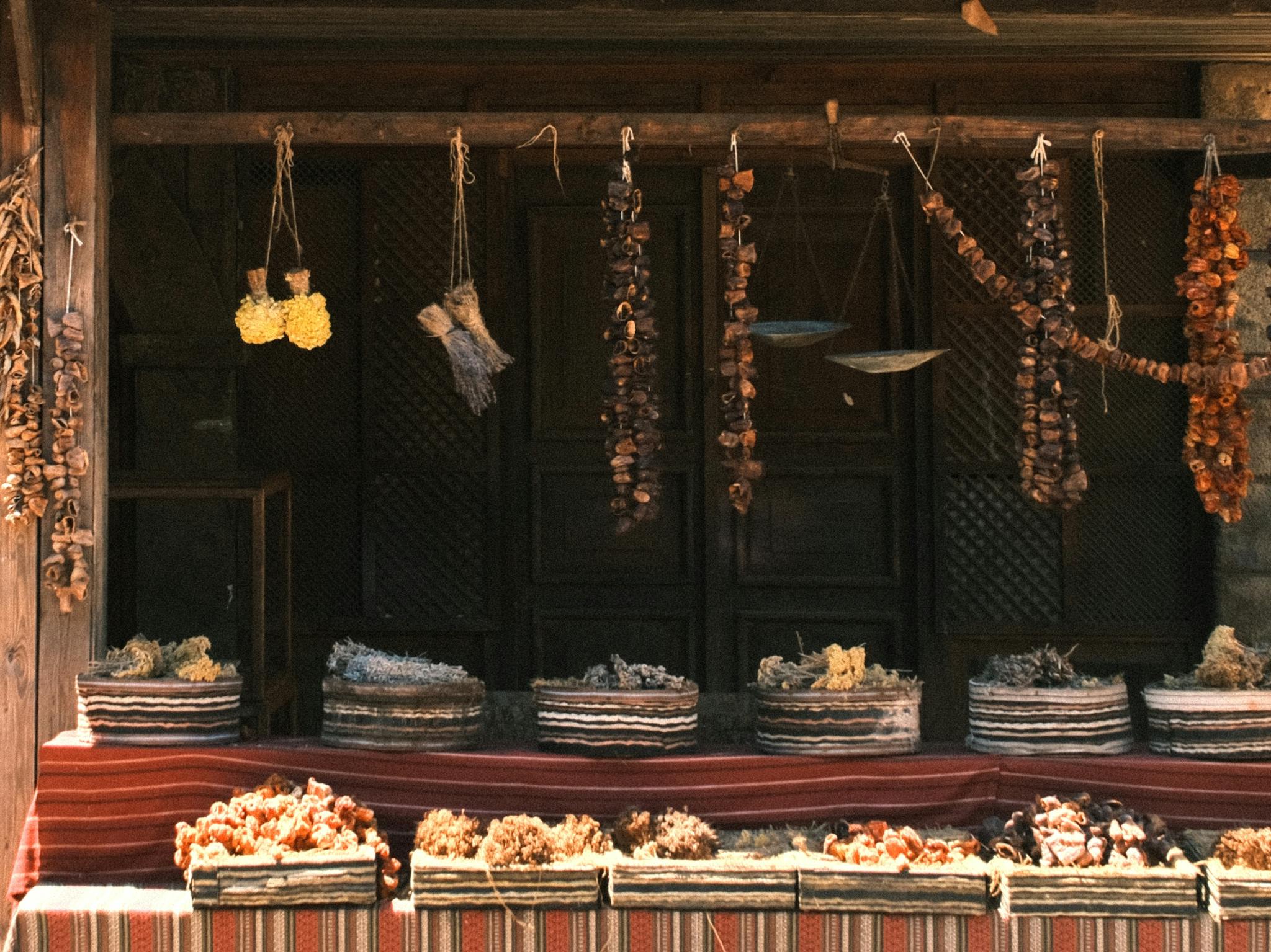 Rustic market stall displaying dried herbs and mushrooms in baskets with warm tones.